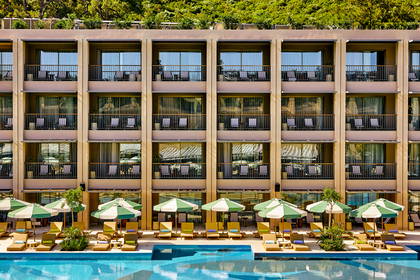 Hotel z balkonami, basenem, leżakami i parasolami.