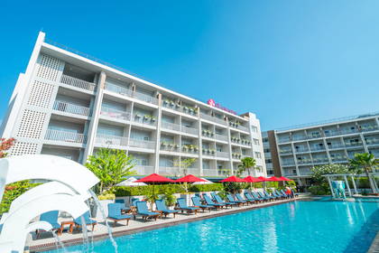Hotel z basenem i strefą relaksu z leżakami oraz parasolami.