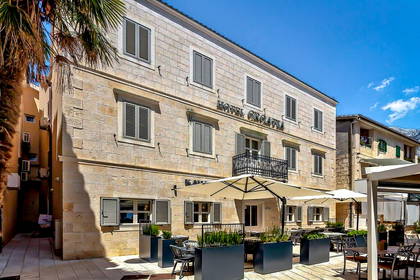 Hotel Croatia z zewnątrz. Widoczne parasole i miejsca do siedzenia.