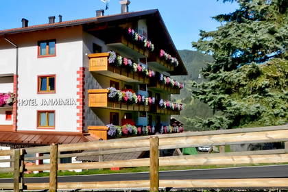 Hotel Janmaria z balkonami ukwieconymi kwiatami, widok zza drewnianego płotu.