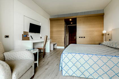 Pokój hotelowy z łóżkiem, biurkiem i fotelem.
