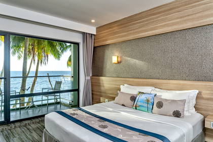 Pokój hotelowy z balkonem i widokiem na ocean oraz palmy.