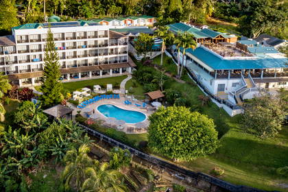 Hotel z basenem otoczony zielenią, widok z góry.