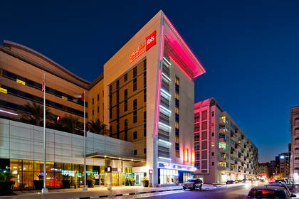 Hotel Ibis w Dubaju oświetlony nocą czerwonymi neonami.