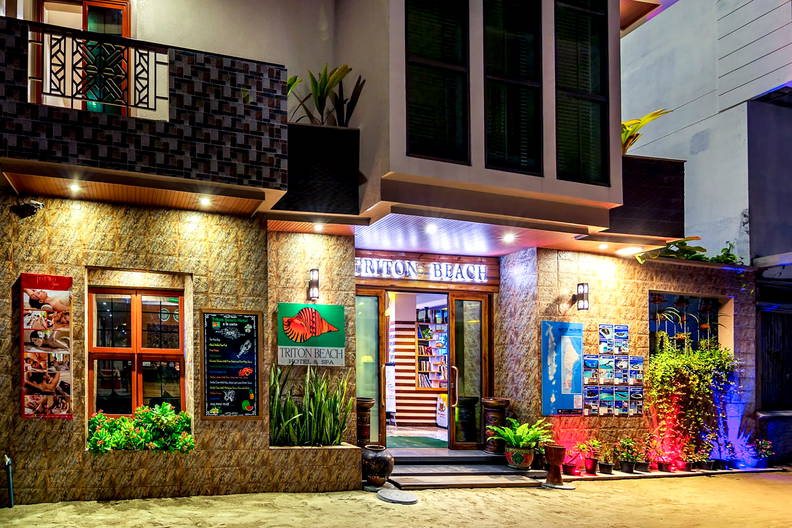 Nocą oświetlone wejście do hotelu Triton Beach Hotel & Spa.