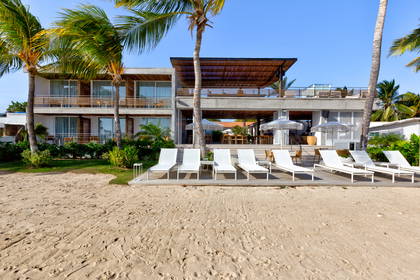 Hotel na plaży z leżakami i palmami.
