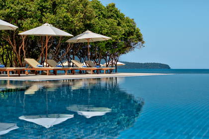 Basen bez krawędzi z leżakami i parasolami.