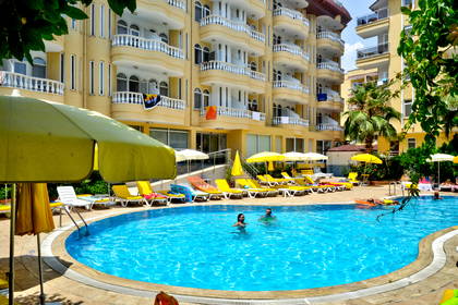 Kompleks hotelowy z basenem, w którym pływają ludzie.