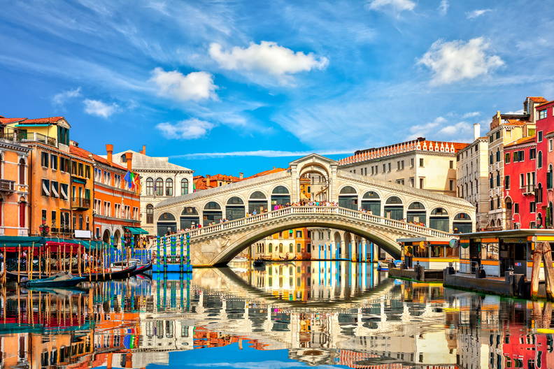 Most Rialto w Wenecji i kolorowe budynki odbijające się w wodzie.