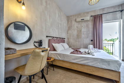 Jasny pokój hotelowy z łóżkiem, biurkiem i balkonem.