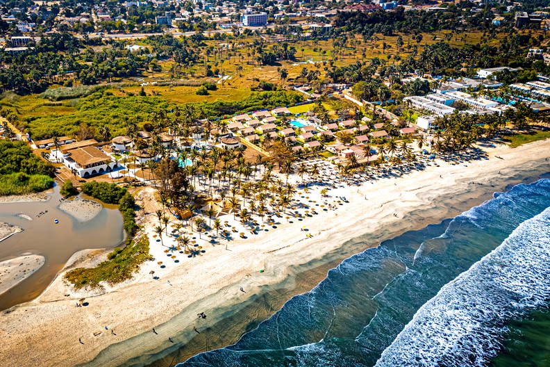 Plaża z palmami i budynkami widziana z góry. W tle błękitny ocean.