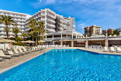 Basen hotelowy z leżakami. W tle budynek.