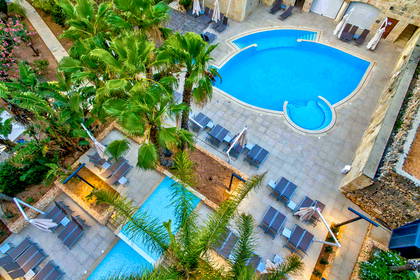 Hotelowy basen z palmami, leżakami i parasolami, widok z góry.