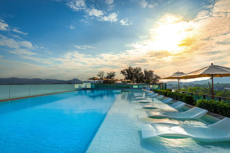 Basen z leżakami w wodzie i widokiem na morze oraz góry.