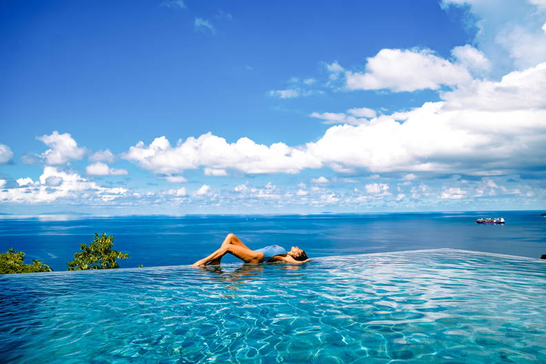 Kobieta w basenie bez krawędzi z widokiem na morze.