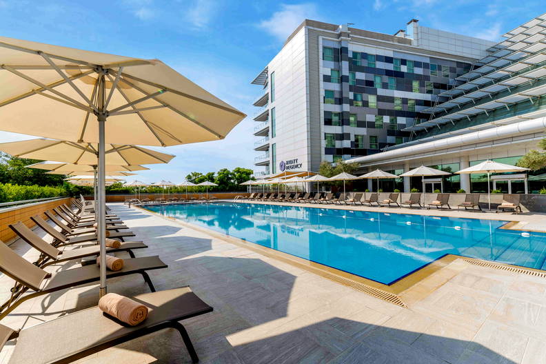Basen z leżakami i parasolami przed hotelem Hyatt Regency.