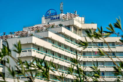 Biały hotel z niebieskimi balkonami na tle nieba.