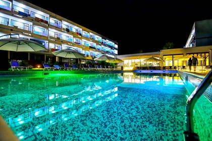 Oświetlony basen hotelowy nocą.