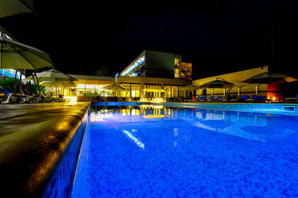 Hotel z basenem i leżakami nocą.