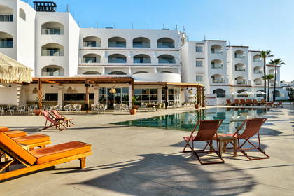 Hotel z basenem i leżakami do opalania.