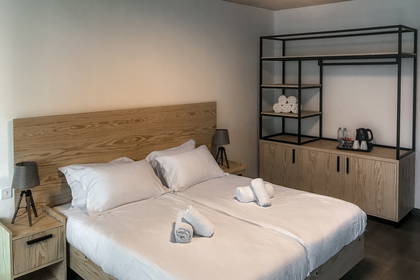 Pokój hotelowy z dwoma łóżkami, szafkami nocnymi i regałem na ścianie.