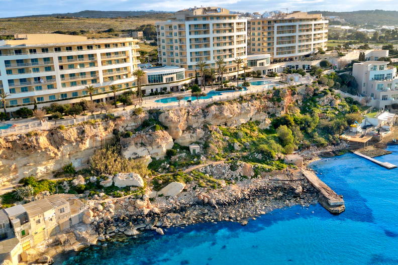 Widok z lotu ptaka na nadmorski hotel, klify i turkusowe morze.