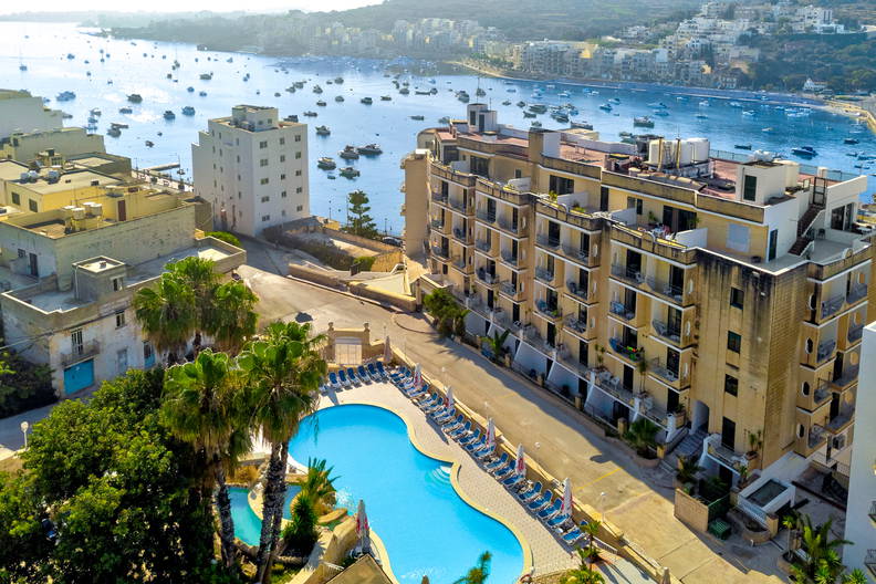 Hotel z basenem i morze z łodziami, widok z góry.