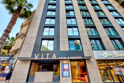 Fasada hotelu Vita Hotel & Rooftop z palmą.