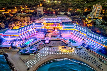 Nocna panorama oświetlonego hotelu, plaży i morza.