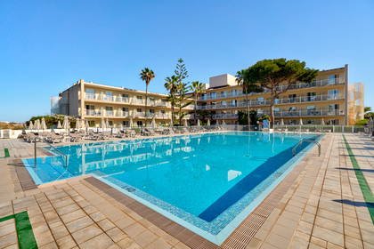 Basen z leżakami i palmami w hotelu.