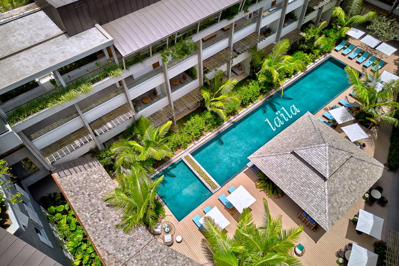 Hotelowy basen otoczony palmami i budynkami, widok z góry.