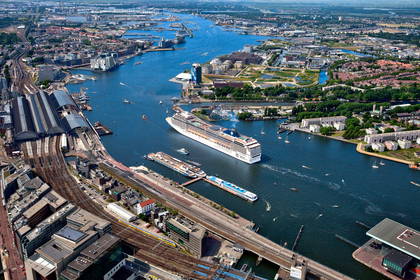 Panorama Amsterdamu z dużym statkiem wycieczkowym.