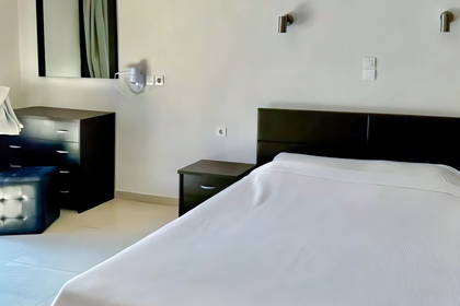 Jasny pokój hotelowy z łóżkiem i meblami.