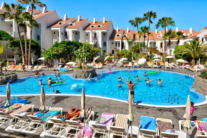 Kompleks hotelowy z basenem i palmami.