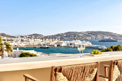 Widok na miasto Mykonos z balkonu, na którym stoją wino i owoce.