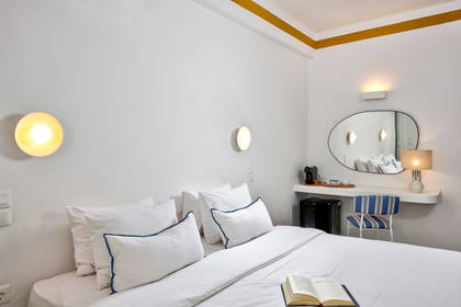 Jasny pokój hotelowy z łóżkiem, toaletką i krzesłem.