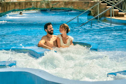 Uśmiechnięta para relaksuje się w jacuzzi w parku wodnym.