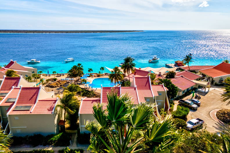 Widok z góry na nadmorski kurort z basenem i łodziami na oceanie.