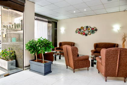 Recepcja hotelowa z brązowymi fotelami, sofą i roślinami.