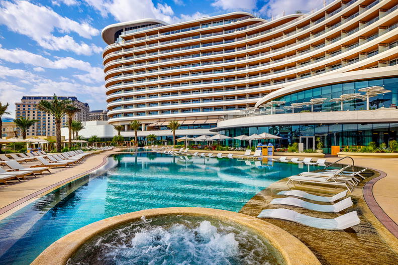 Hotel z basenem i jacuzzi w słoneczny dzień.