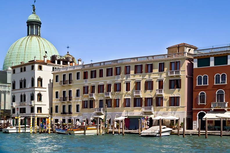 Kanał w Wenecji z budynkami wzdłuż brzegu. W tle zielona kopuła.