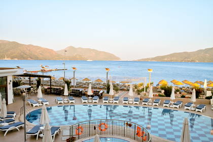 Hotelowy basen z widokiem na plażę, morze i góry.