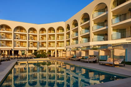 Kompleks hotelowy z basenem i leżakami do opalania.