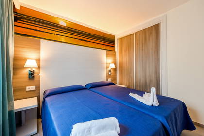 Pokój hotelowy z dwoma łóżkami i ręcznikiem ułożonym w kształt łabędzia.