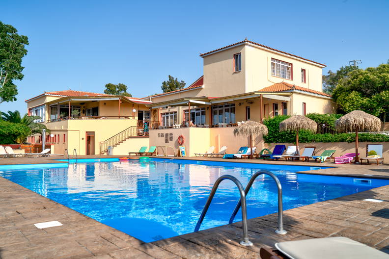 Basen hotelowy z leżakami i parasolami w słoneczny dzień.