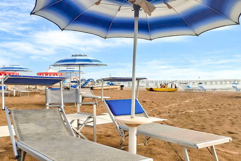 Plaża z leżakami i parasolami w biało-niebieskie pasy.