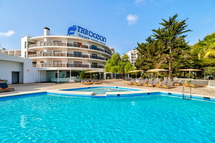 Basen hotelowy z leżakami. W tle budynek hotelu.