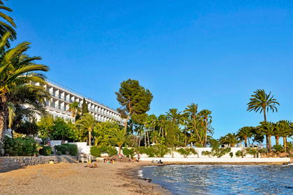 Plaża z palmami i hotel w słoneczny dzień.
