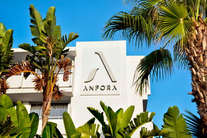 Hotel Anfora: biały budynek na tle nieba, otoczony palmami.