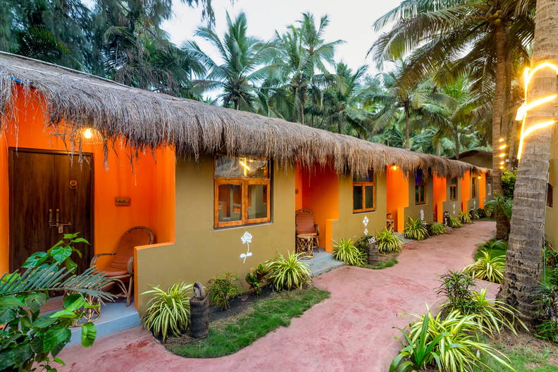 Domy letniskowe kryte strzechą wśród palm.